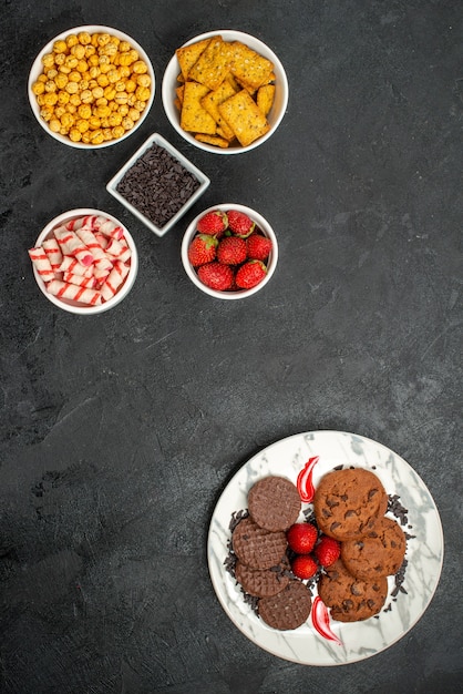 Top view yummy choco biscuits with different snacks on the dark background sweet cookie tea