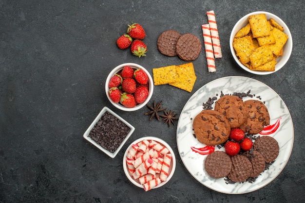 Top view yummy choco biscuits with different snacks on dark background sweet cookies tea