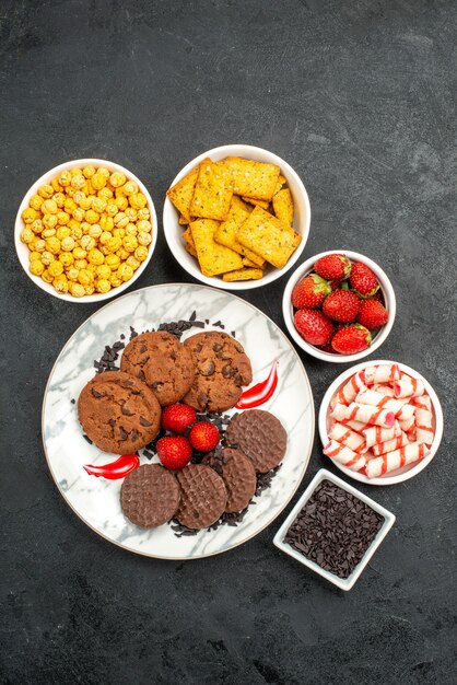 Top view yummy choco biscuits with different snacks on dark background tea sweet cookie