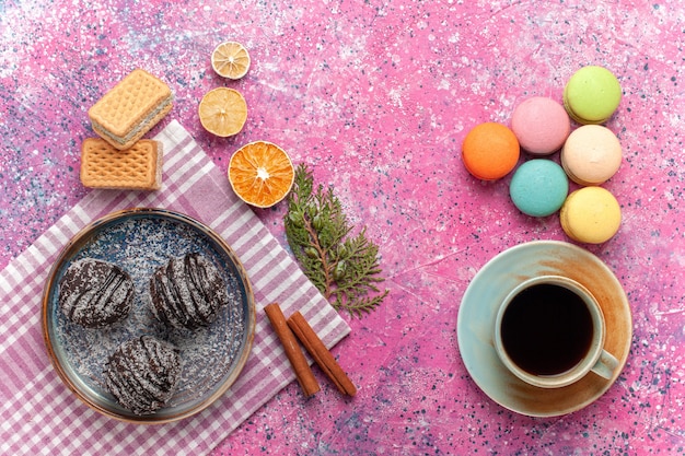 Top view yummy chocolate cakes with cup of tea and french macarons on pink