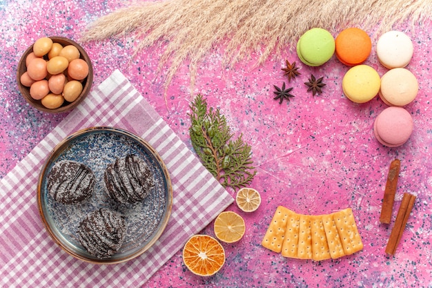 Free photo top view yummy chocolate cakes with french macarons on pink