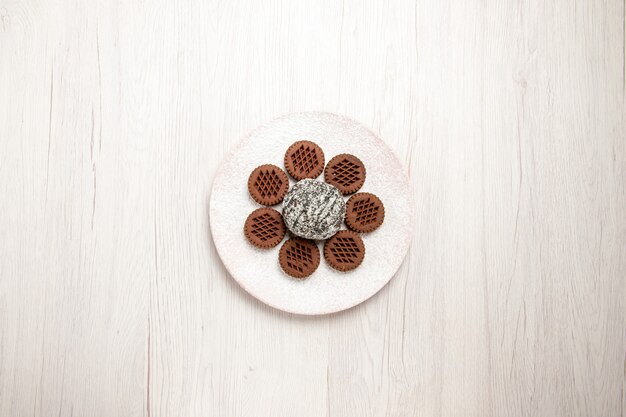 Top view yummy chocolate cookies with little cocoa cake on a white desk