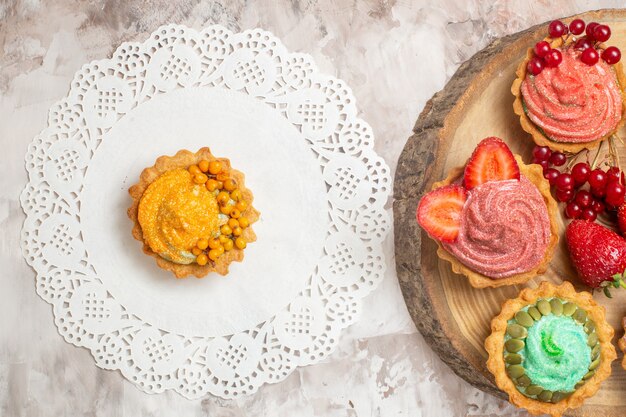 Top view yummy cream cakes with fruits on light table dessert biscuit sweet cakes