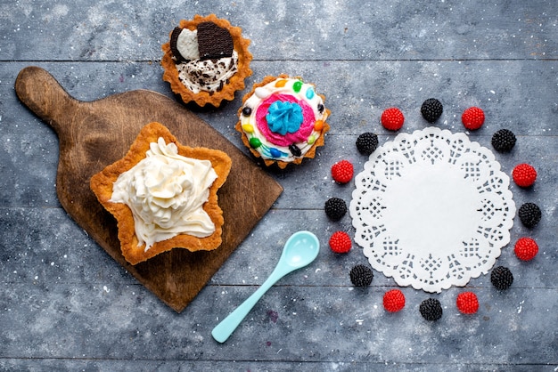 Top view yummy creamy cake star shaped with cookie cakes berries and blue spoon on the light background cake biscuit cream sweet tea