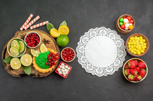 Top view yummy creamy cake with candies and fruits on a dark background sweet cookie biscuit