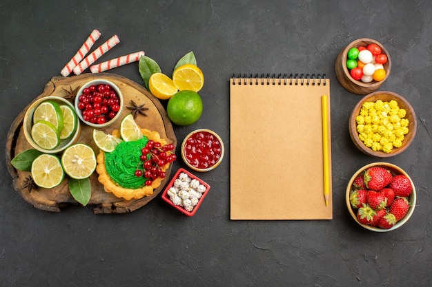 Top view yummy creamy cake with candies and fruits on dark background sweet cookie biscuit