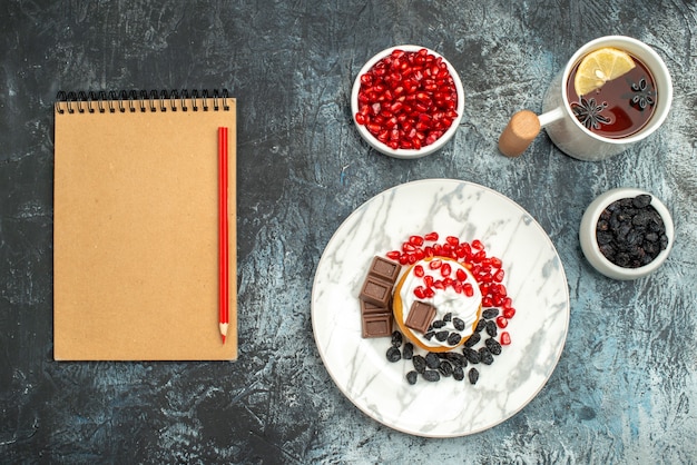 Free Photo top view yummy creamy cake with choco biscuits and cup of tea on light-dark background