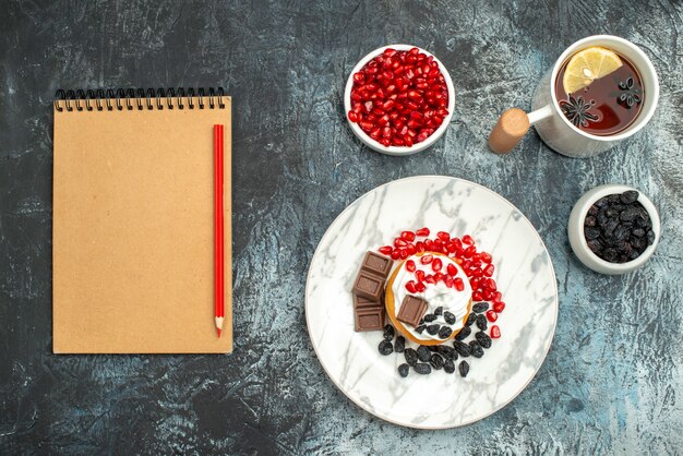 Top view yummy creamy cake with choco biscuits and cup of tea on light-dark background