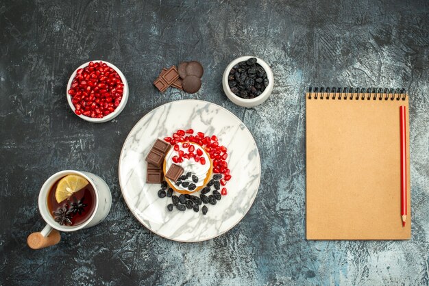 Top view yummy creamy cake with choco biscuits and cup of tea on light-dark background