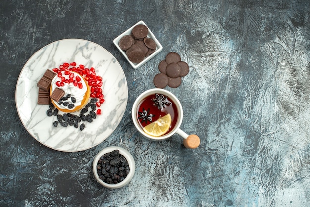 Free photo top view yummy creamy cake with choco biscuits and cup of tea on light-dark background