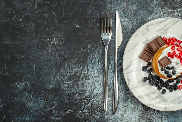 Free photo top view yummy creamy cake with raisins and cup of tea on light-dark background