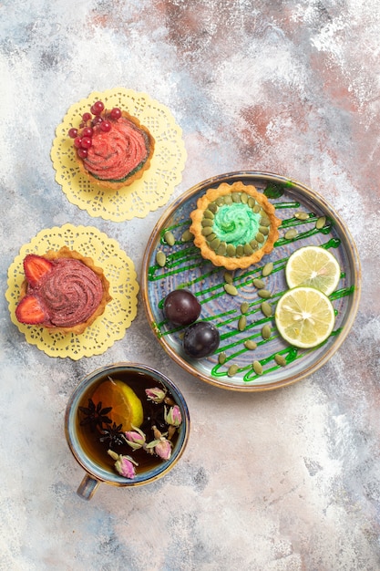 Free photo top view yummy creamy cakes with cup of tea on light background sweet candy biscuit