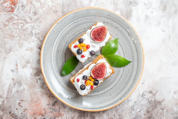 Top view yummy creamy cakes with fresh fruits on light background