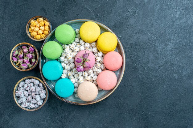 Top view yummy french macarons with candies on grey