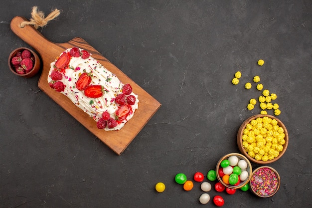 Free photo top view of yummy fruity cake with candies on black