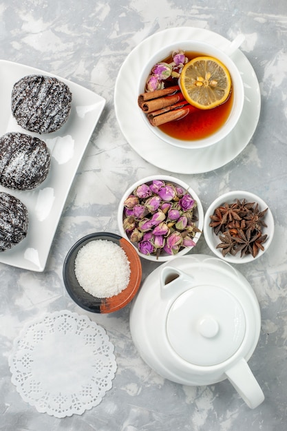 Free photo top view yummy little cakes chocolate cakes with cup of tea on light-white background