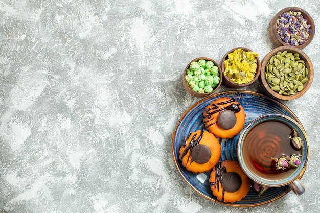 Top view yummy little cakes with cup of tea on a white surface cake biscuit cookie dessert sweet tea