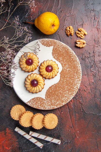 Top view yummy little cookies inside plate on the dark table cake sweet biscuits sugar