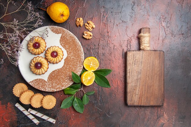 Top view yummy little cookies with fruits on a dark table sugar cake sweet biscuit