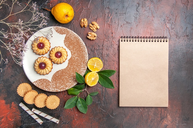 Top view yummy little cookies with fruits on the dark table sugar cake sweet biscuit