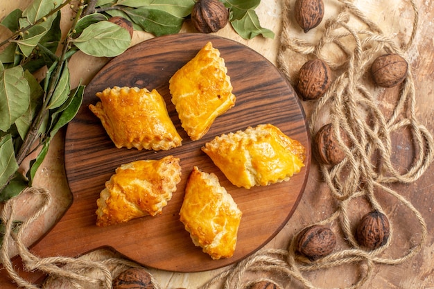 Top view of yummy nut pastries with fresh walnuts on brown desk