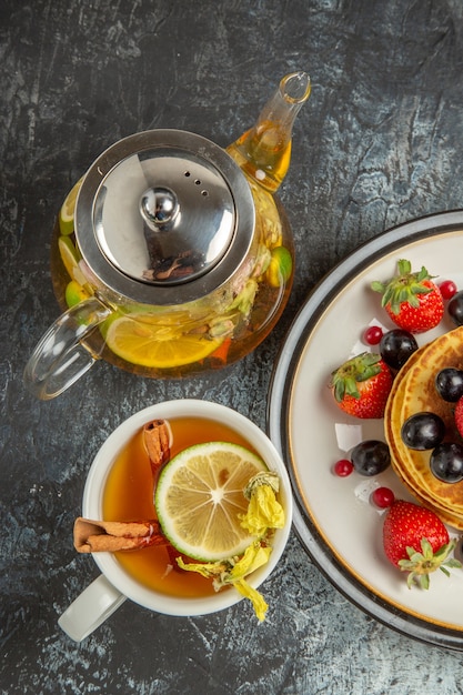 Free photo top view yummy pancakes with fruits and tea on light desk sweet fruit breakfast