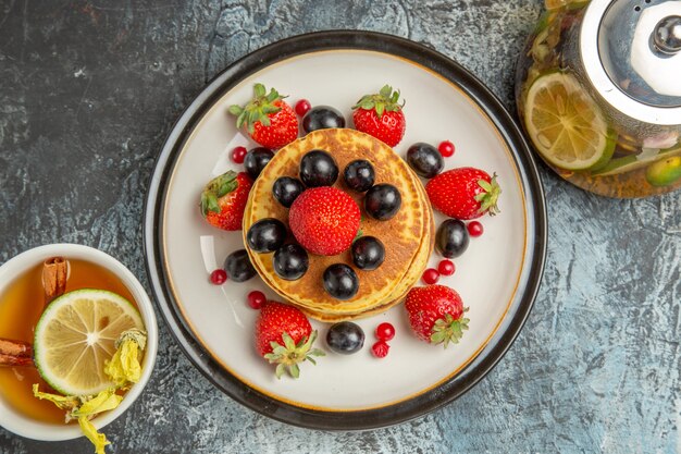 Top view yummy pancakes with fruits and tea on a light