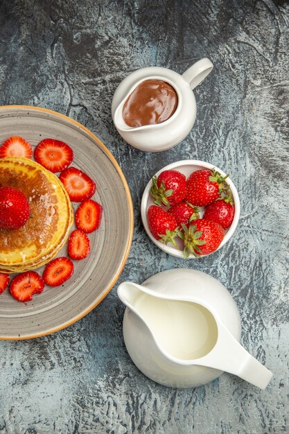 Top view yummy pancakes with honey and strawberries on a light