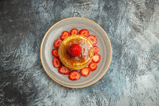 Top view yummy pancakes with honey and strawberries on a light