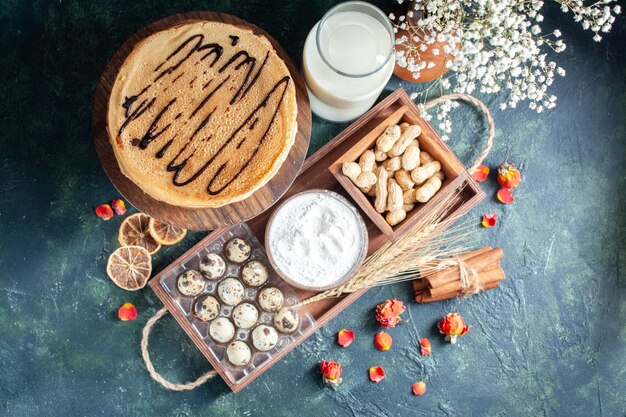 Top view yummy pancakes with milk and nuts on dark-blue background morning pie dessert sweet cake honey breakfast milk