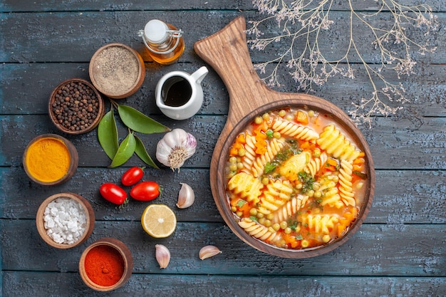 Top view yummy pasta soup from spiral italian pasta with seasonings on dark-blue desk cuisine pasta soup color dish dinner