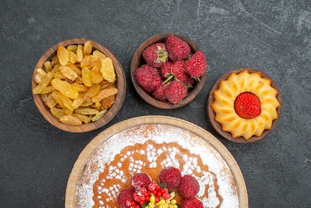 Top view yummy raspberry cake with raisins on grey surface sugar biscuit cake cookie tea sweet pie