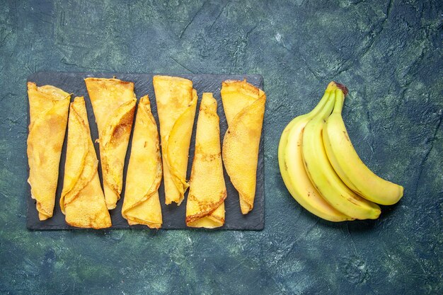 Top view yummy rolled pancakes with bananas on dark background cake dough hotcake color meal pastry pie meat