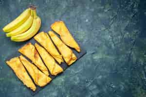 Free photo top view yummy rolled pancakes with bananas on dark background cake dough hotcake color meal pastry sweet pie meat free space