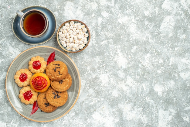 Top view yummy sand biscuits with cookies and cup of tea on white