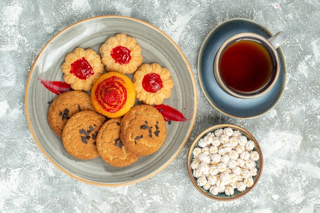 Top view yummy sand biscuits with cookies and cup of tea on white