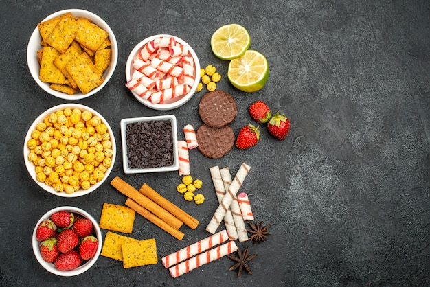 Top view yummy snacks with crackers pieces of chocalate slices of lemon on the black background with free space