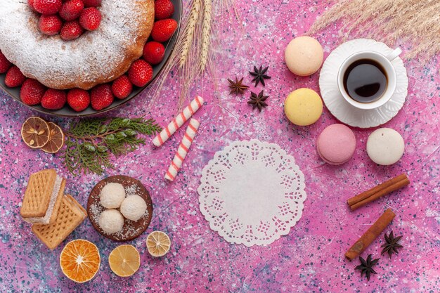 Top view yummy strawberry pie with french macarons and cup of tea on pink