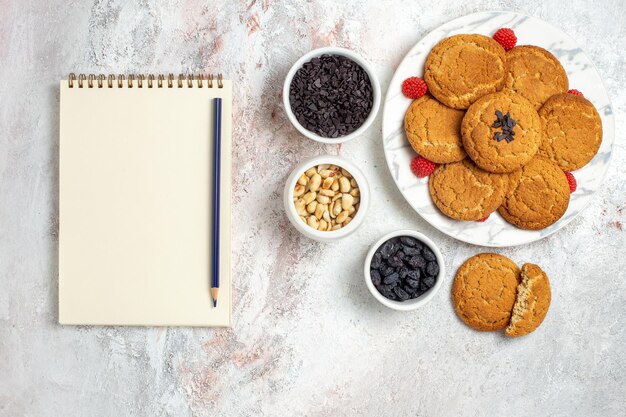 Top view of yummy sugar cookies with nuts on a white surface