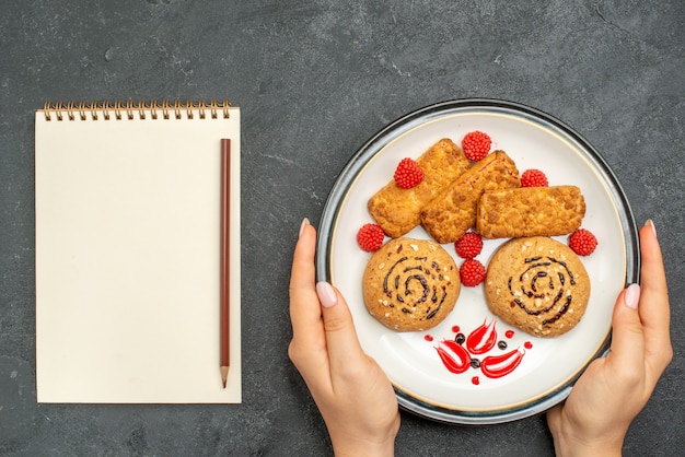 Free photo top view yummy sweet cookies inside plate on grey desk biscuit sweet sugar cake cookie tea