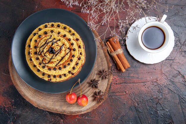 Top view yummy sweet pancakes with cup of tea on dark surface