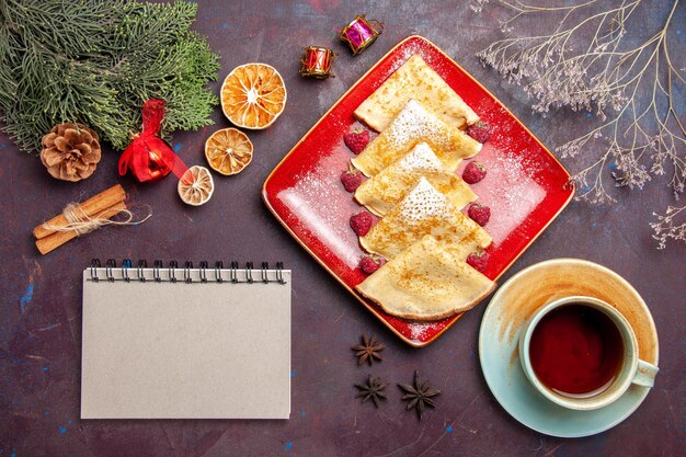 Top view of yummy sweet pancakes with raspberries and cup of tea on black