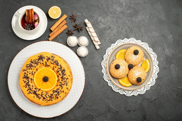 Top view yummy sweet pie with cookies and cup of tea on grey surface sweet pie cake dessert biscuit tea