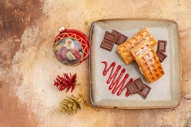 Top view yummy waffle cakes with chocolate bars on a brown background