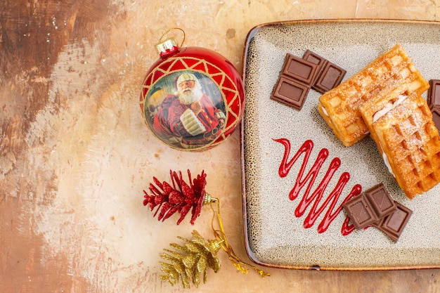 Top view yummy waffle cakes with chocolate bars on brown background