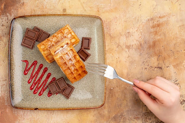 Top view yummy waffle cakes with chocolate bars on brown desk