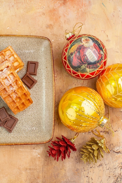 Free photo top view yummy waffle cakes with chocolate and new year tree toys on a light background