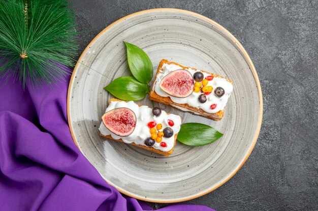 Top view yummy waffle cakes with fruits on dark background