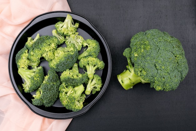 top viewbroccoli in black pan over pink cloth on black stone surface