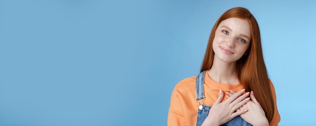 Free photo touched romantic tender cute redhead feminine girl blue eyes tilting head melting heartwarming gesture receive gladly pleasant prest touch heart smiling grateful feel romance love blue background